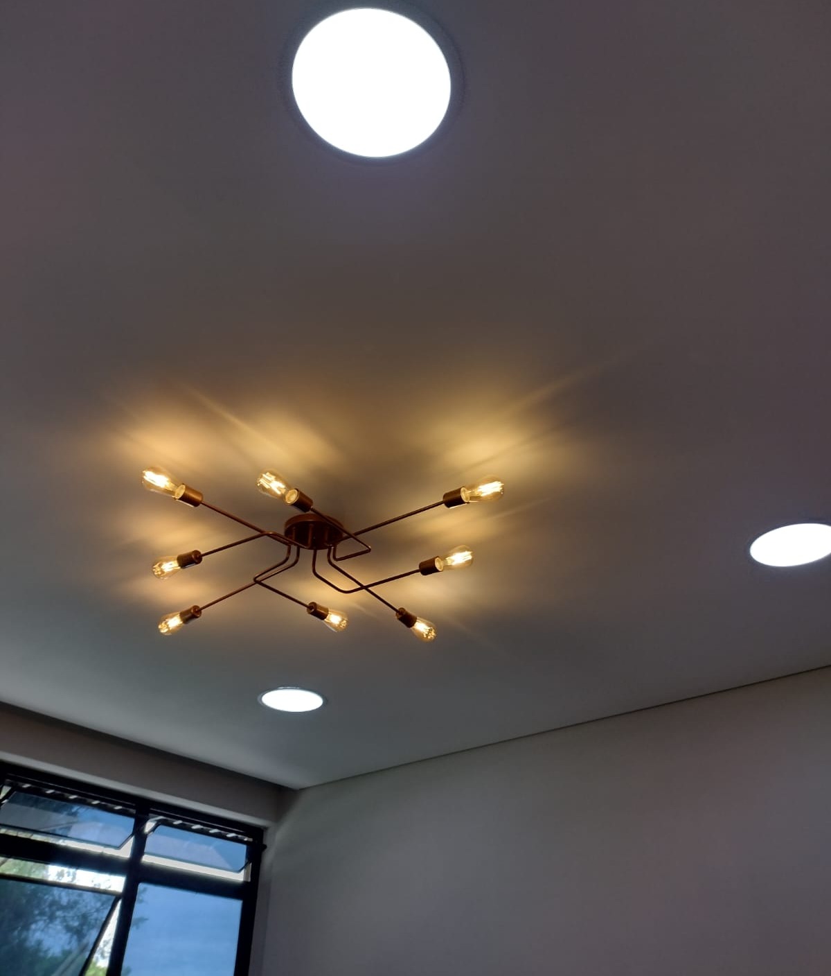 lustre dourado moderno com lâmpadas de filamento acesas instalado em teto branco com luminárias de embutir ace