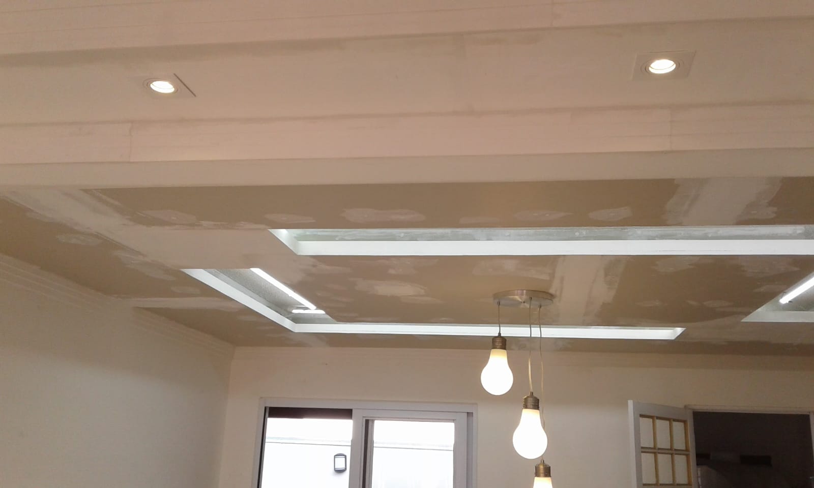 forro de gesso com sancas iluminadas e luminárias pendentes de lâmpadas em ambiente residencial em acabamento