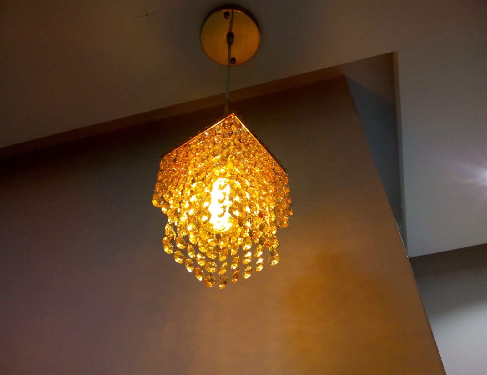 pendente de cristal âmbar aceso, pendurado no teto, fotografado de baixo